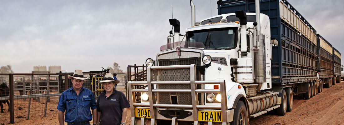 Road train with two farmers standing in front of it.