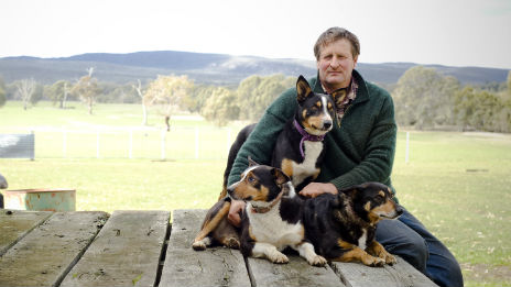 Farmer and three dogs sitting on porch.