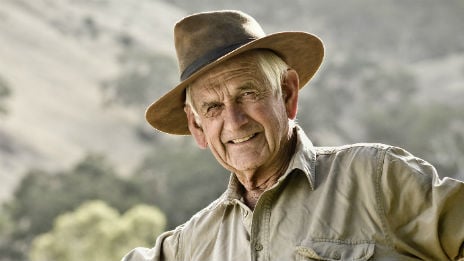 Mature male farmer leaning on fence.