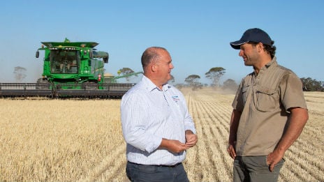 Rural Bank staff member and farmer in paddock with header.