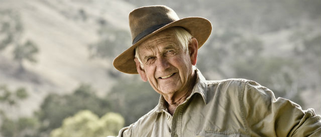 Mature male farmer leaning on fence.