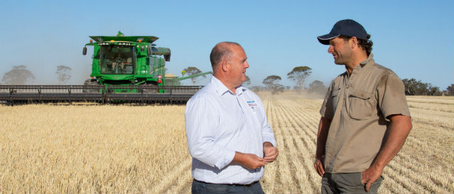 Rural Bank staff member and farmer in paddock with header.